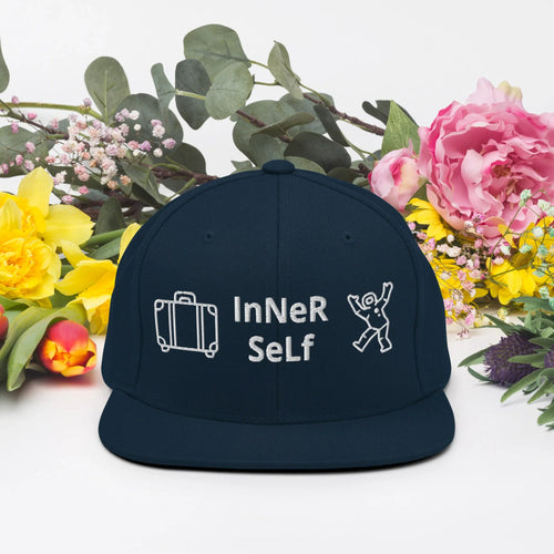 Dark navy snapback cap with 'InNeR SeLf' text and suitcase, astronaut icons, floral background.